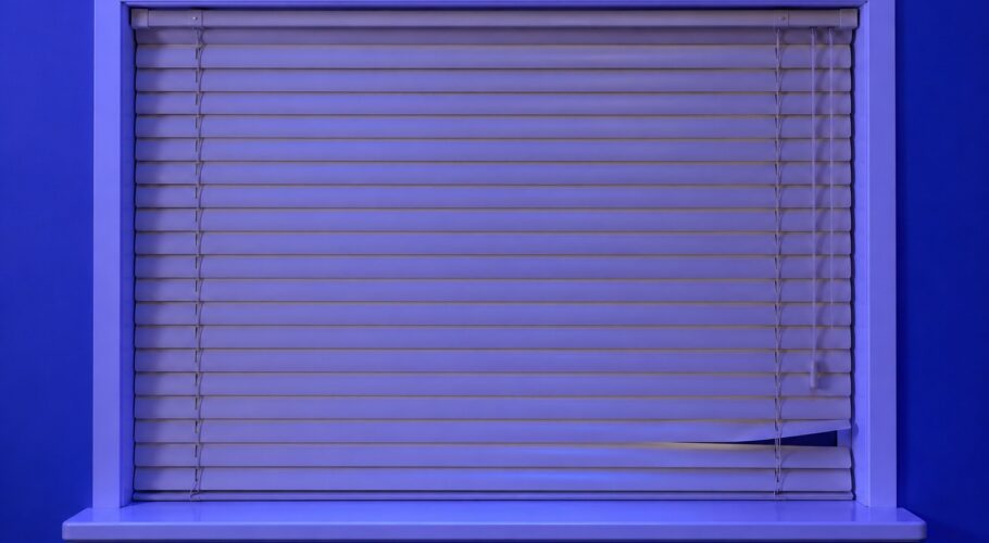 A closed venetian blind with one bent slat leaving a small gap to peek through.