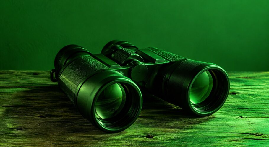 Black plastic binoculars on a wooden table under green light