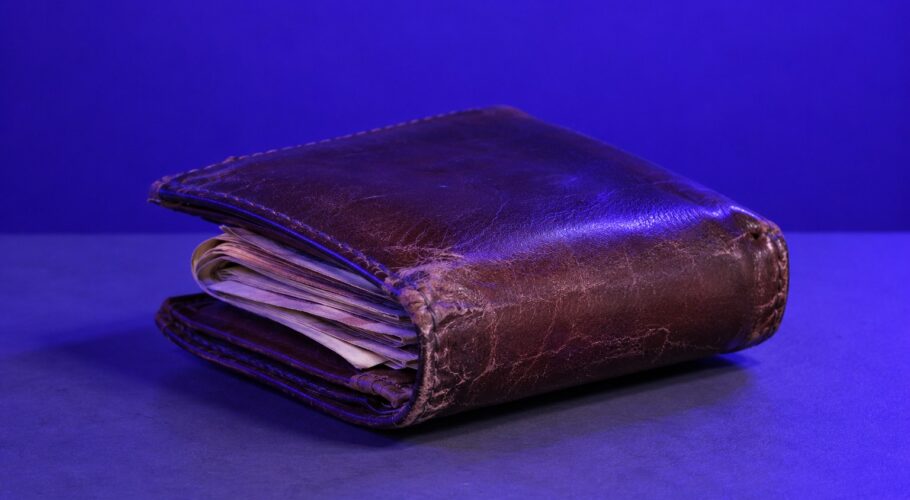 A worn brown leather wallet with notes sticking out.