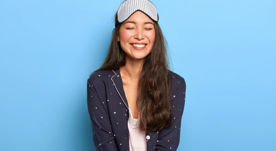 cheerful woman with pleasant toothy smile wears comfortable pyjamas sleep mask enjoys bedtime routine china