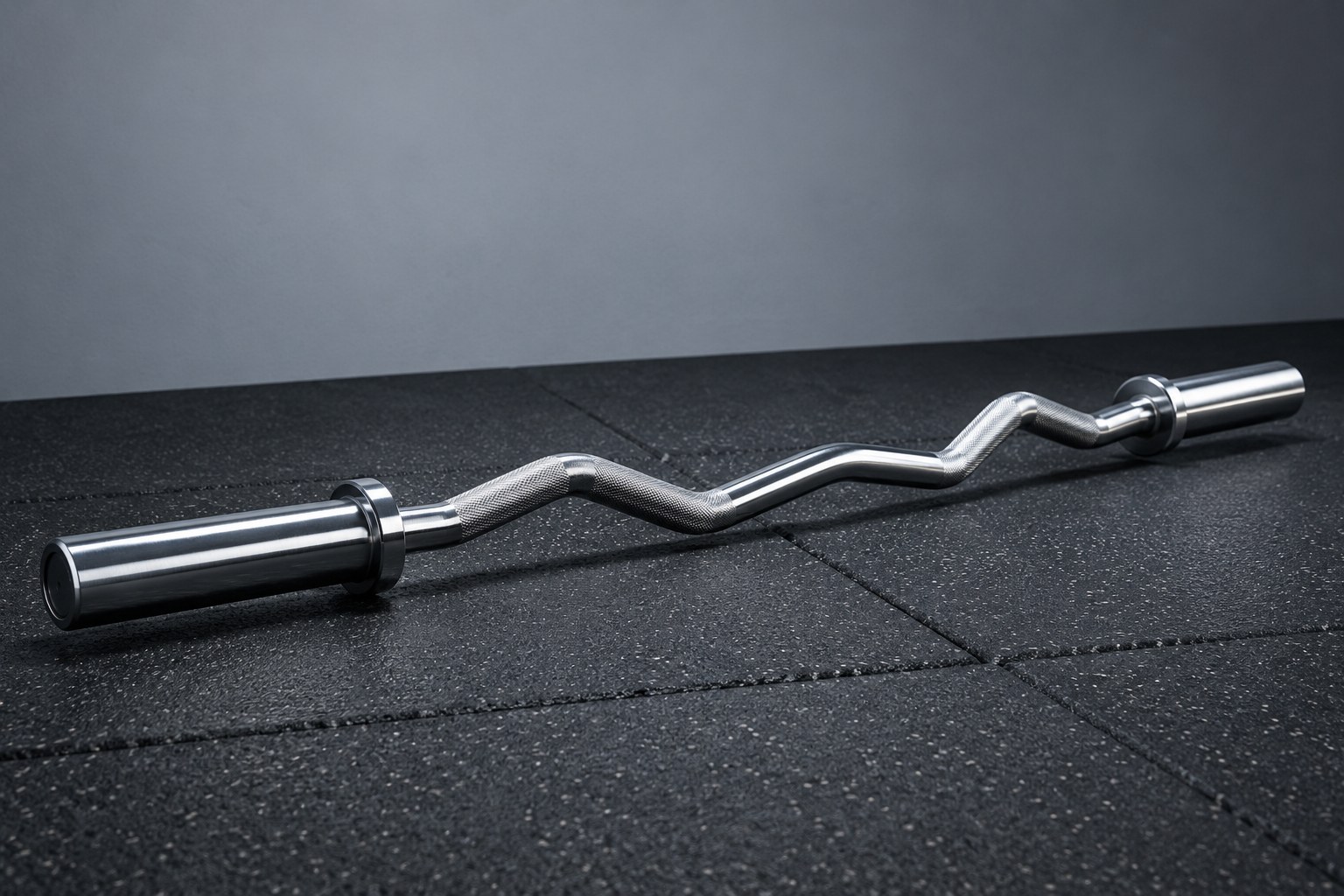 A chrome barbell loaded with black cast iron weight plates on a concrete floor