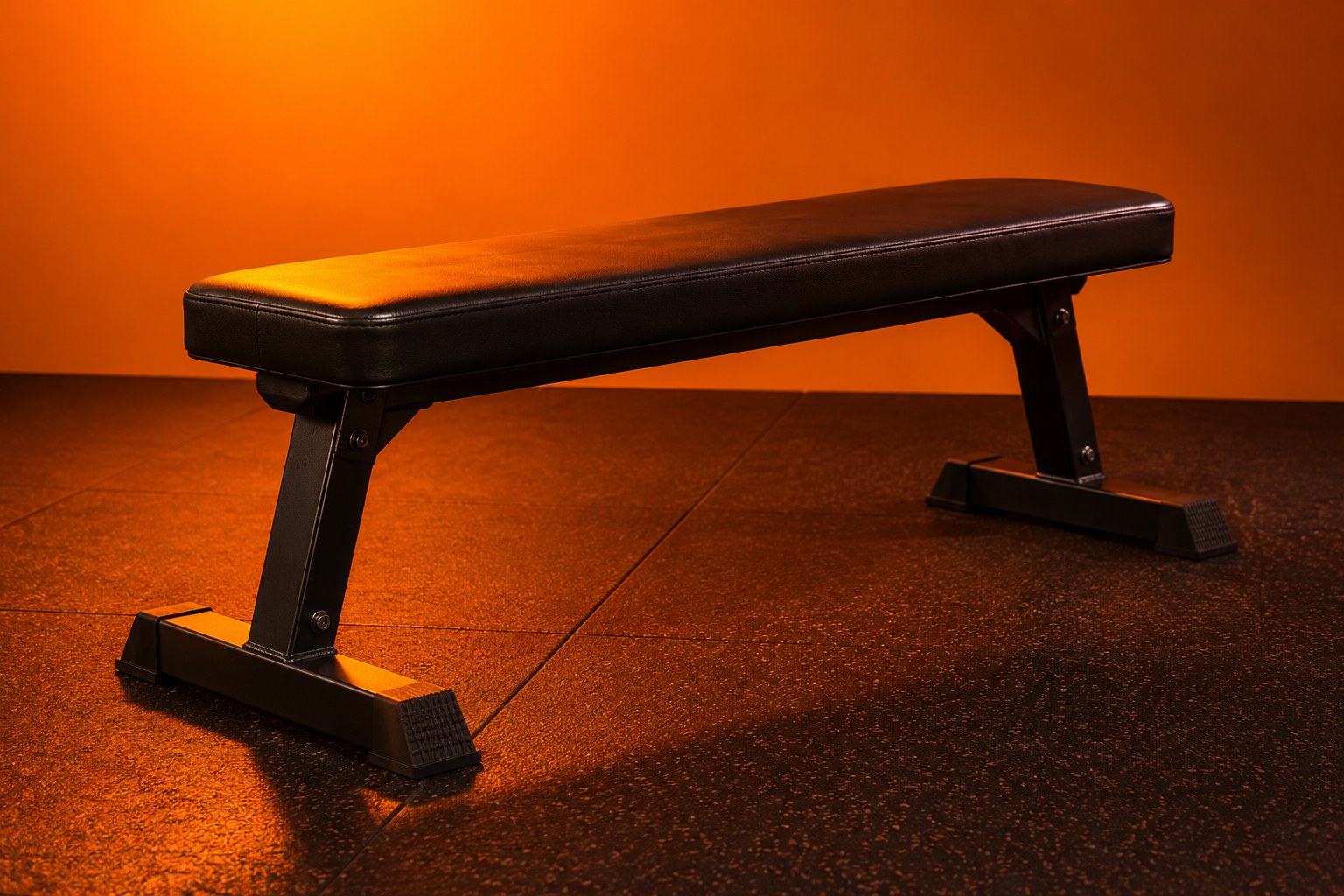 a padded flat gym bench with a black vinyl cover on a rubber floor photographed in a studio