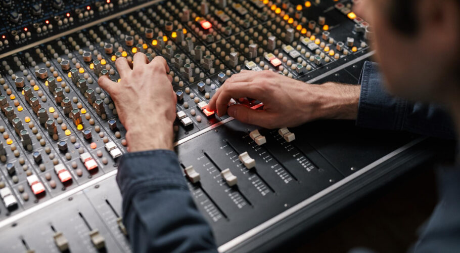 close up male hands operating buttons toggles digital audio workstation recording studio