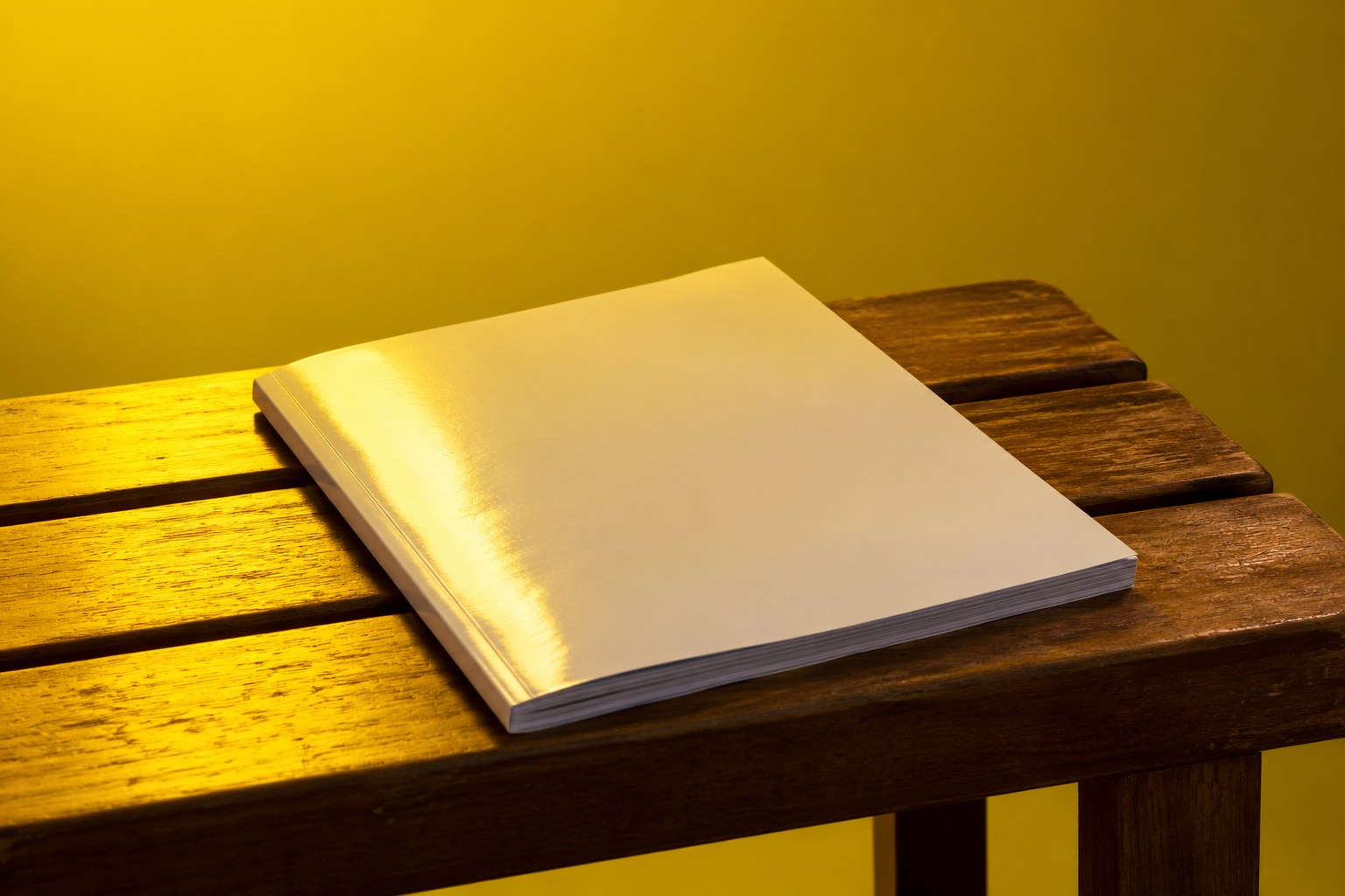 A closed magazine with a blank cover resting on a wooden bench