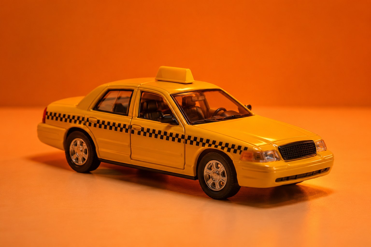 a small yellow toy taxi cab model on a pale surface photographed in a studio