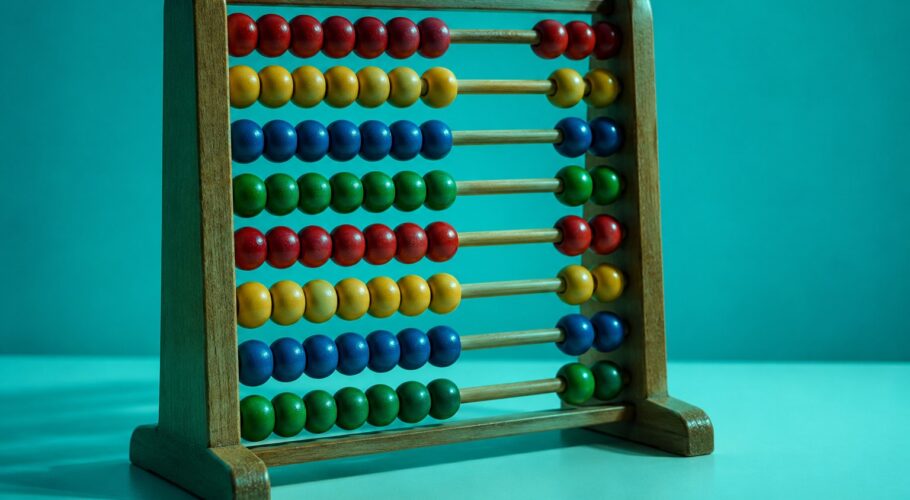 a wooden abacus with plain coloured beads on a pale surface photographed in a studio