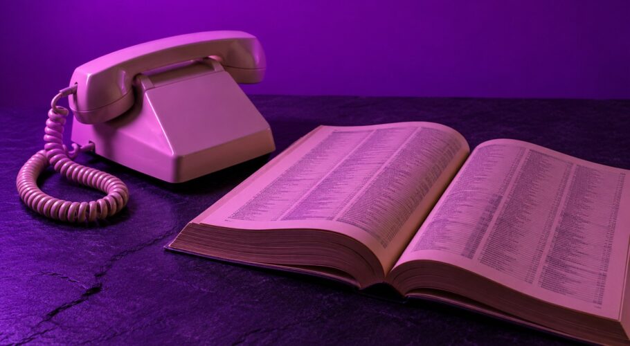 A cream coloured corded telephone resting on a wooden desk