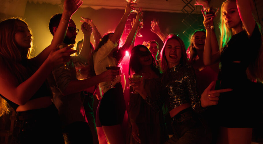 emotions crowd of people raising their hands dancing on dancefloor with neon light night life