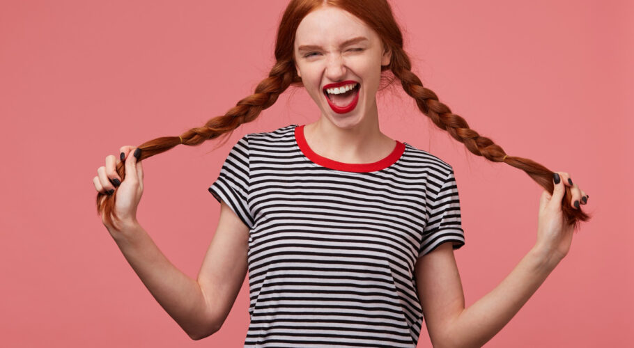 funny joyful girl holding two red haired braids kathryn hands with red lips dressed stripped tshirt dressed