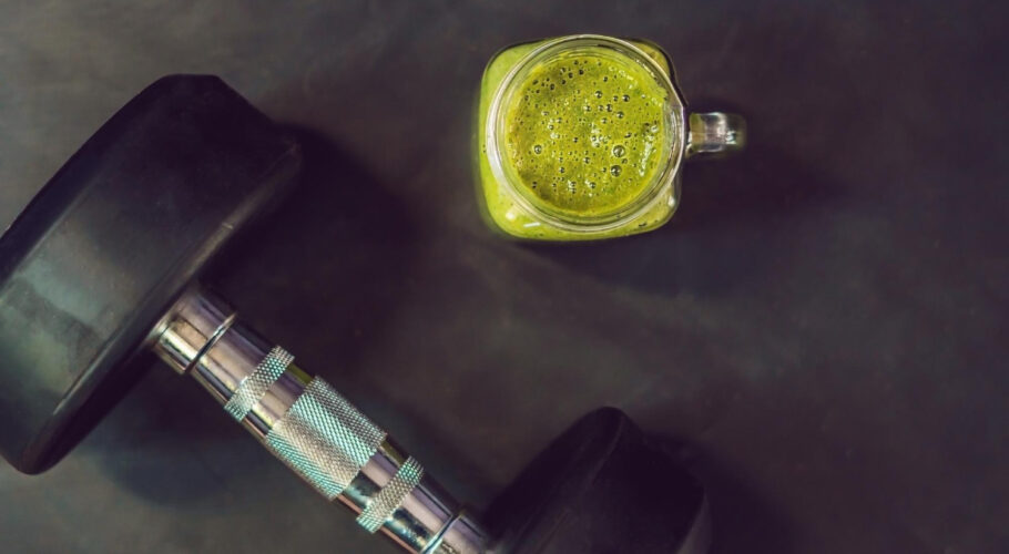 green smoothie with dumbbells at the gym