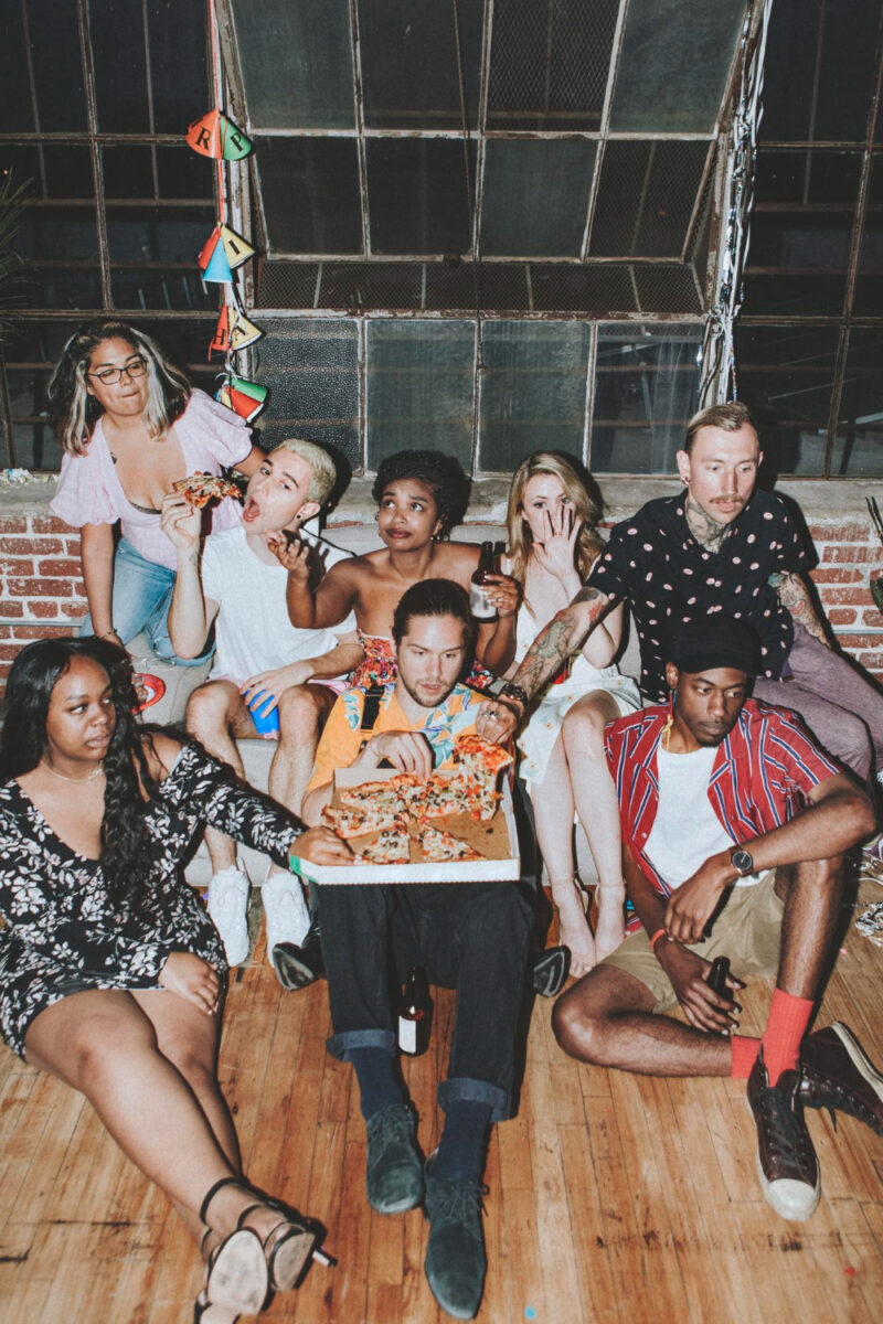 group of diverse friends enjoying pizza at house party