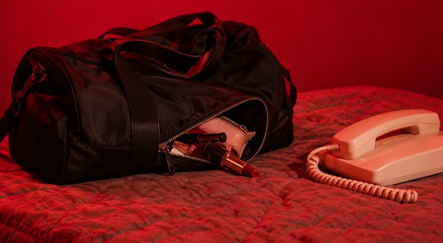 Overnight bag and corded phone on a motel bed after a late night argument