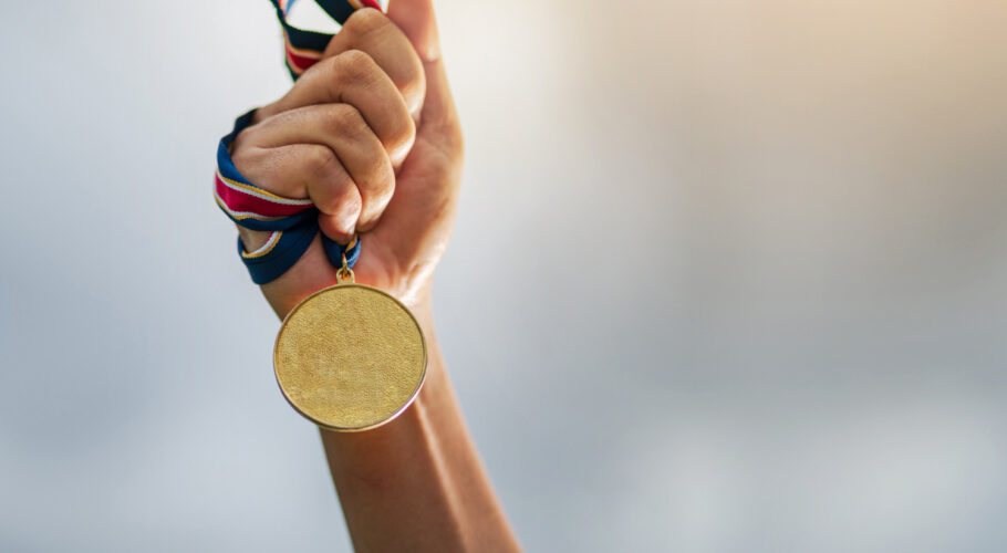 hand holding gold medal to the sky olympics