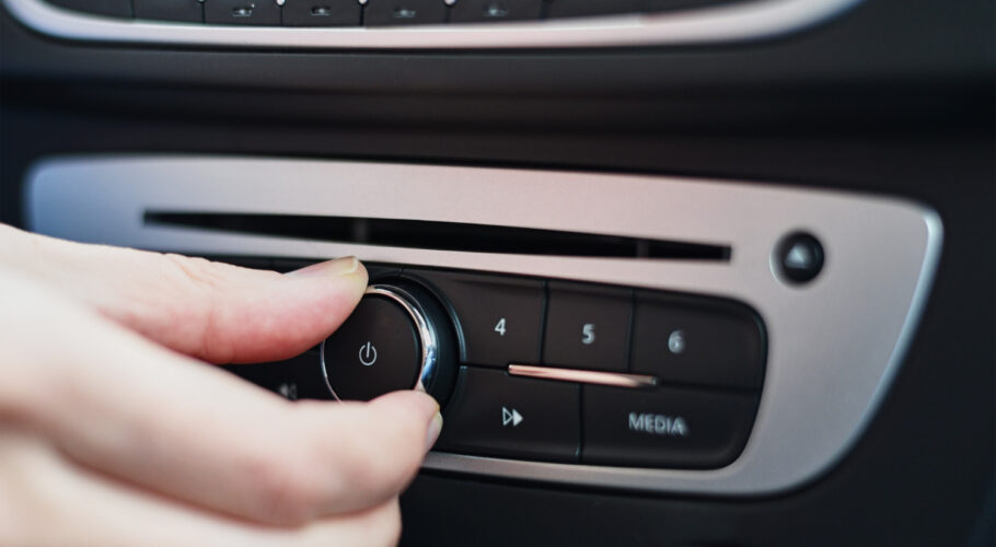 hand pressing a button on a car radio