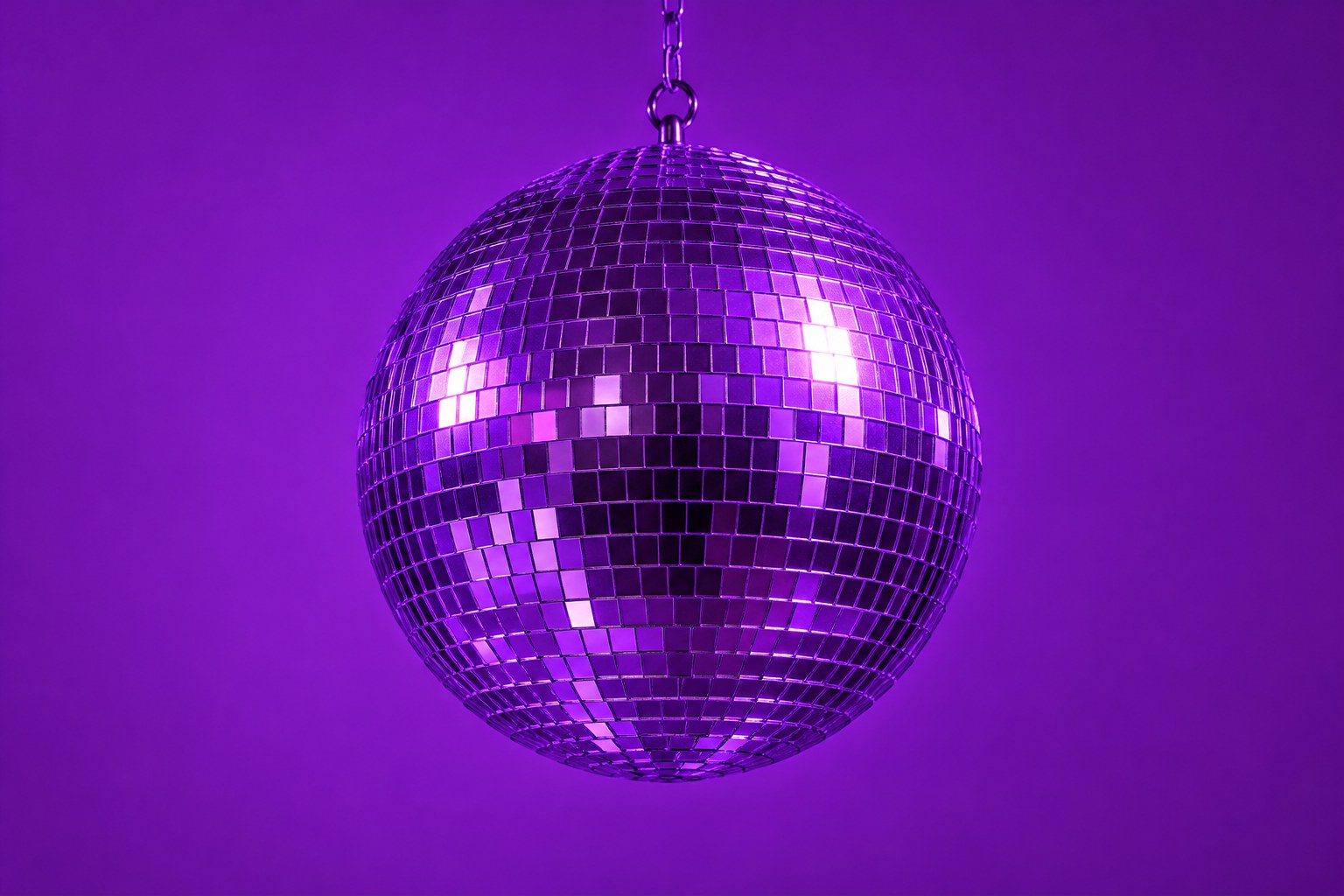 A mirrored disco ball hanging against a plain backdrop under violet light