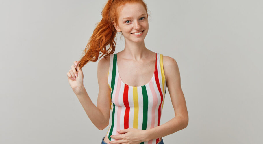 portrait attractive happy girl with ginger pony tail freckles wearing striped colorful swimsuit jeans