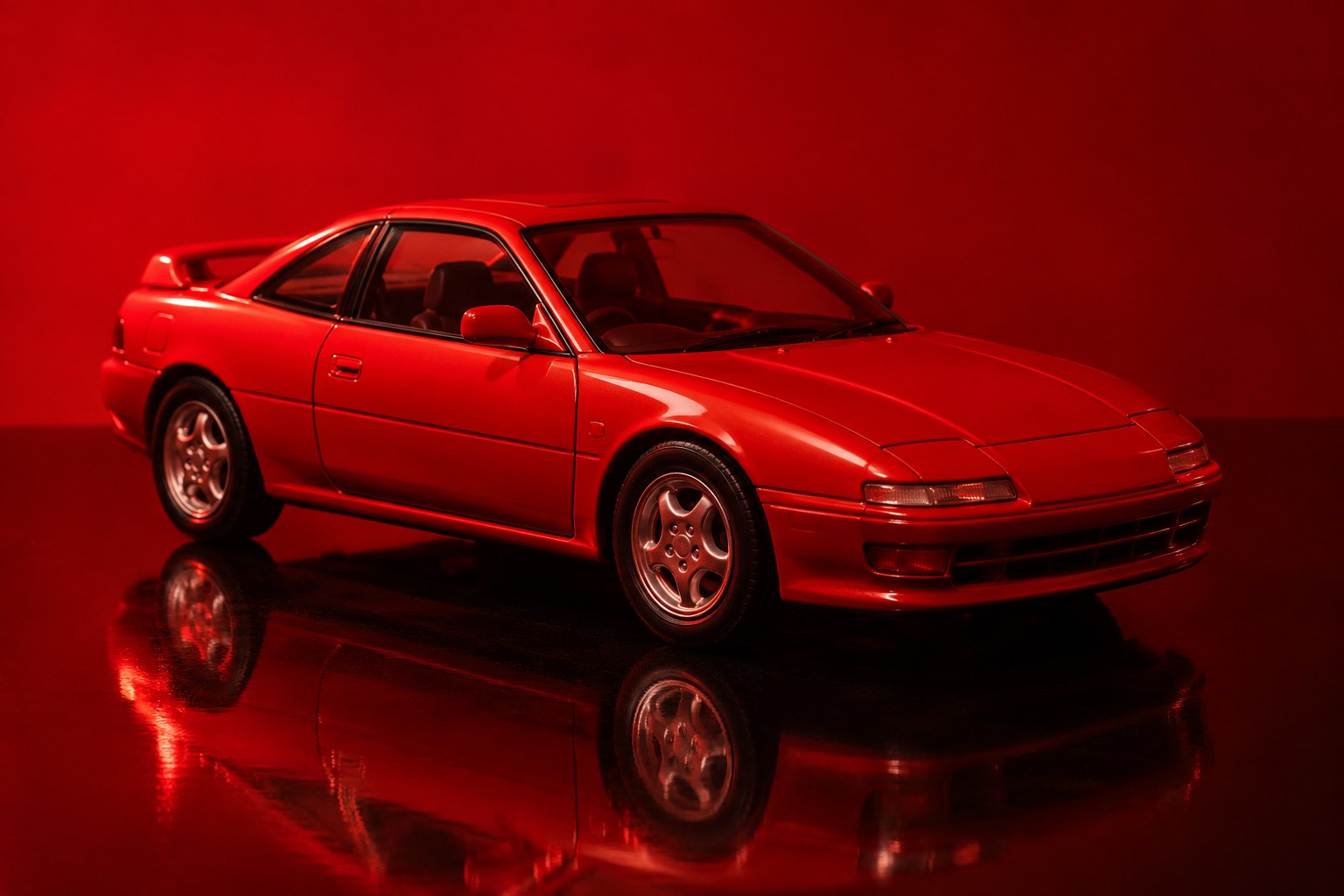 A small red toy coupe sitting on a shiny black surface