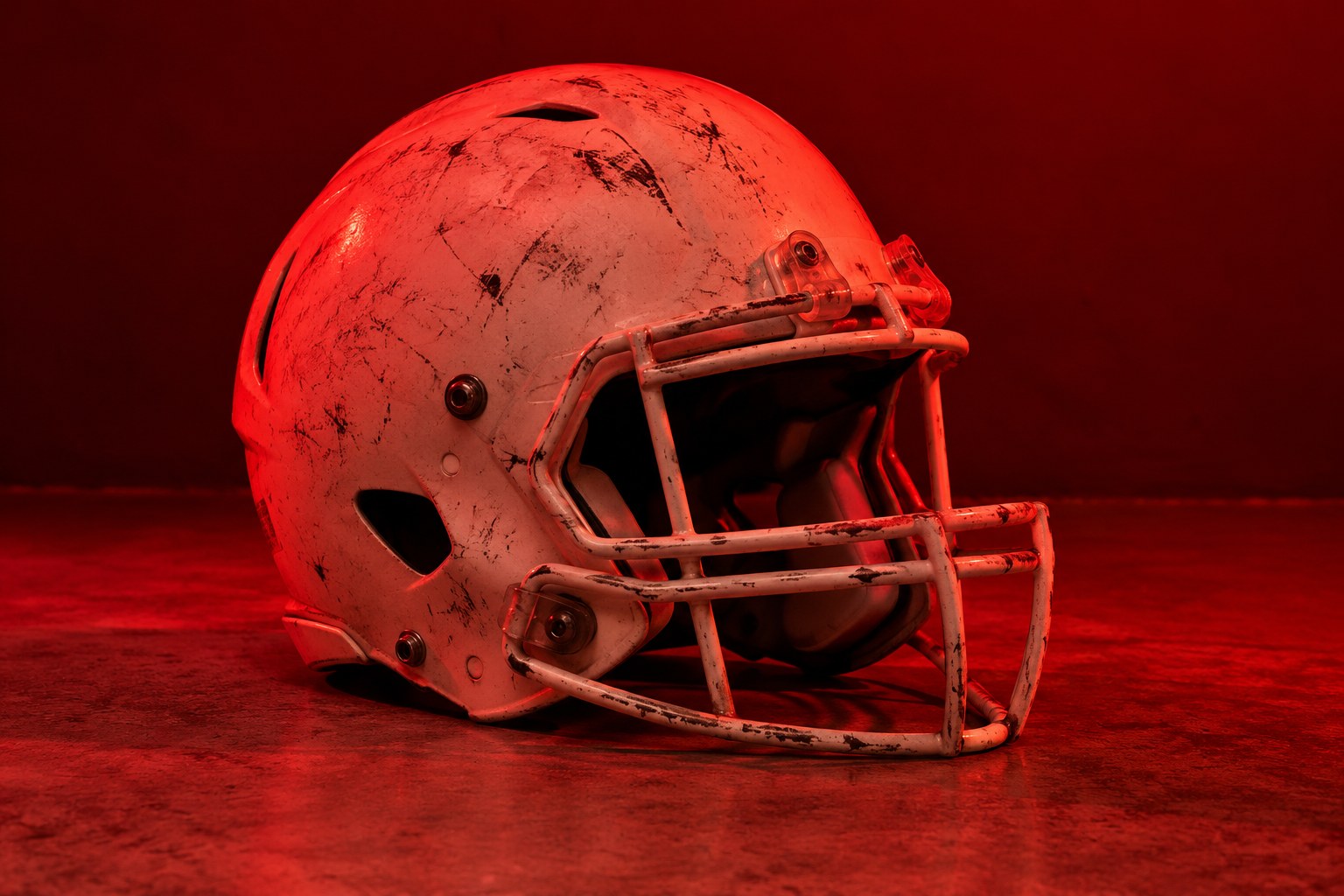A scuffed white gridiron football helmet on a concrete floor
