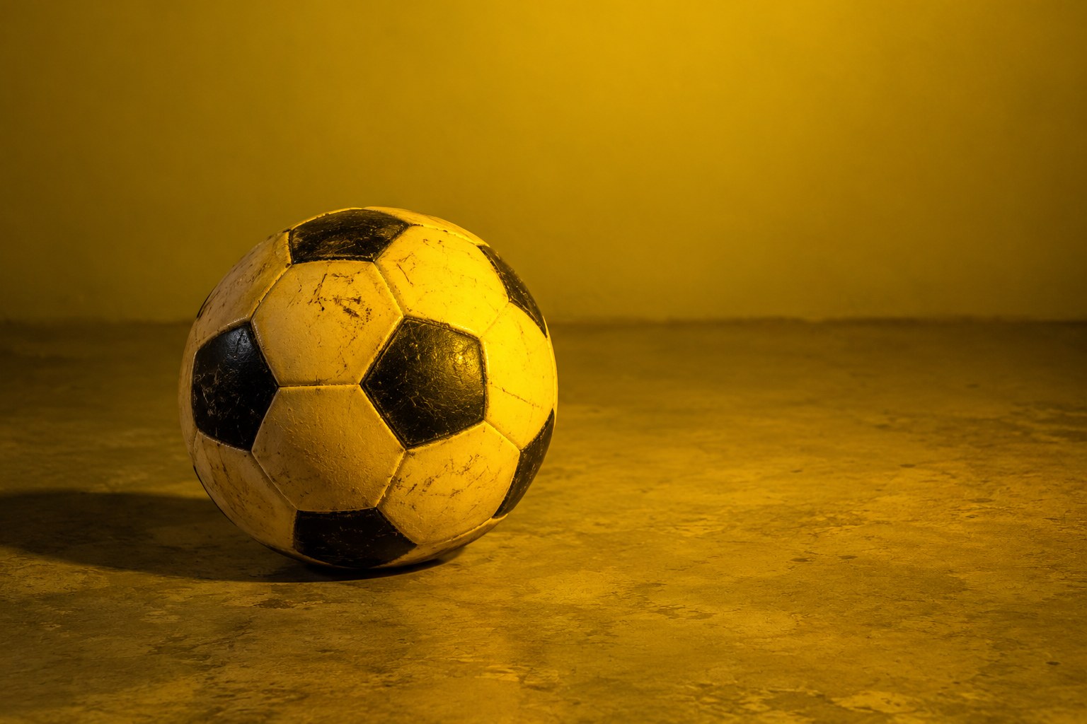 A scuffed plastic soccer ball on a concrete floor