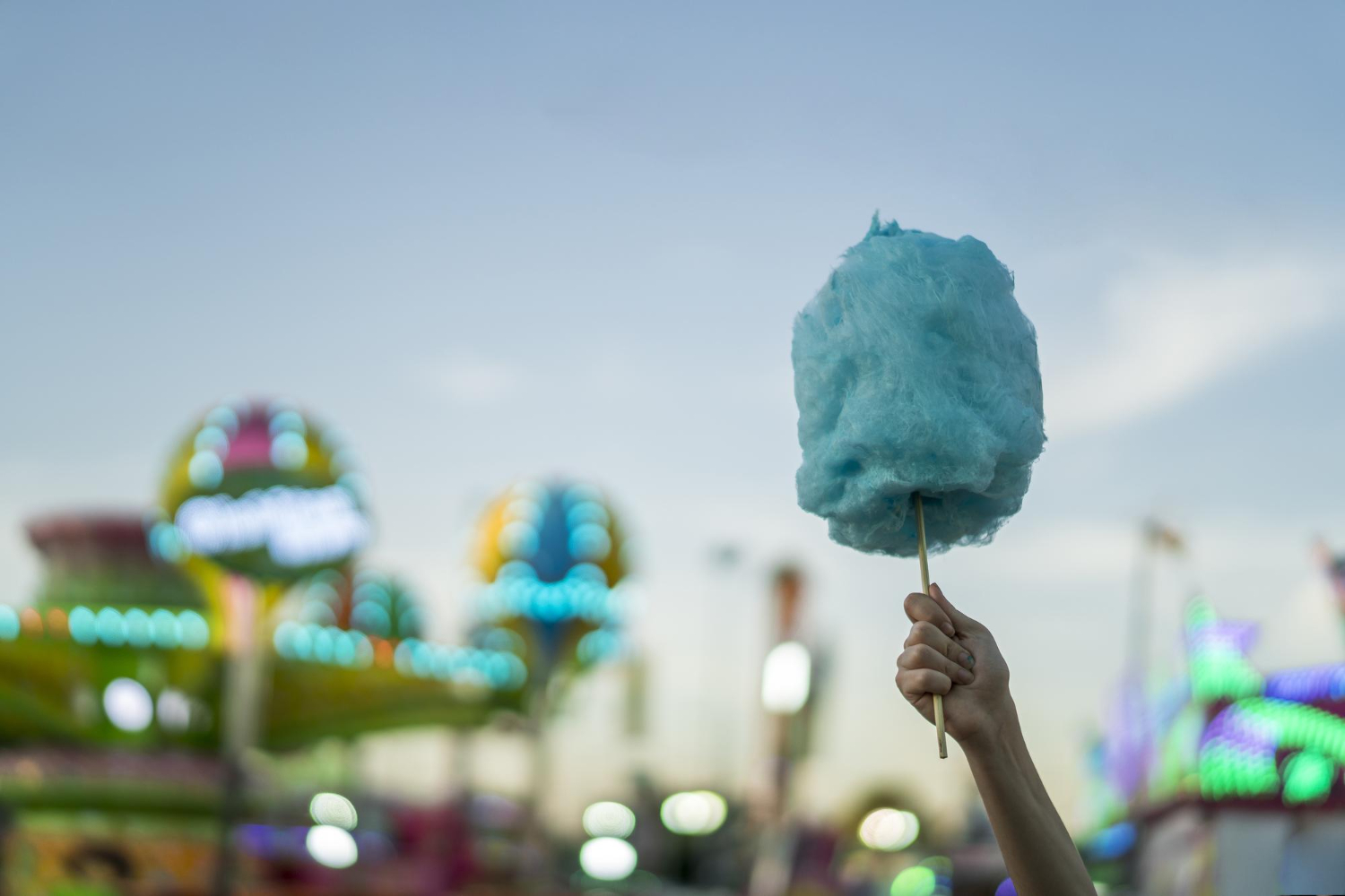 selective focus shot female holding cotton candy amusement park