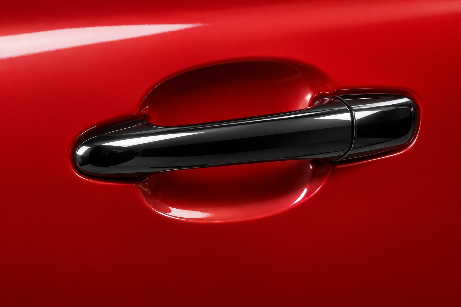 a black chrome car door handle on a red painted panel photographed in a studio