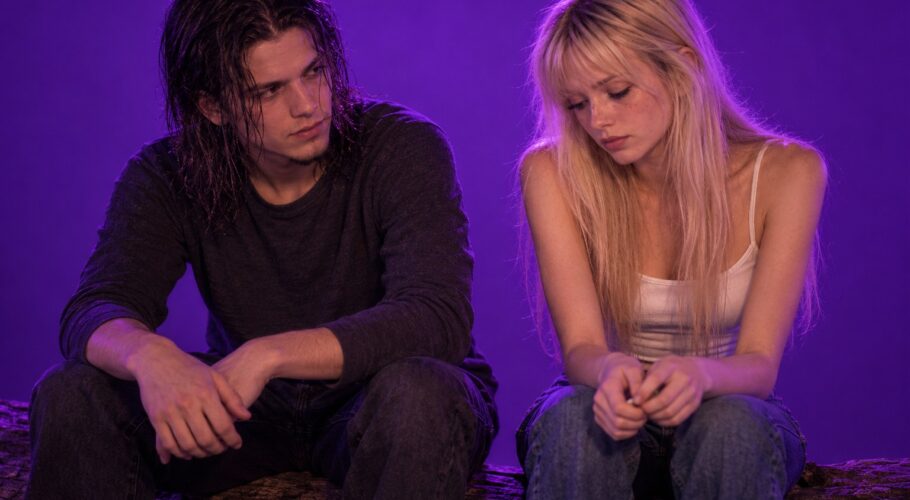 Tony and Lyssa sitting side by side on a log in a serious talk about where they stand