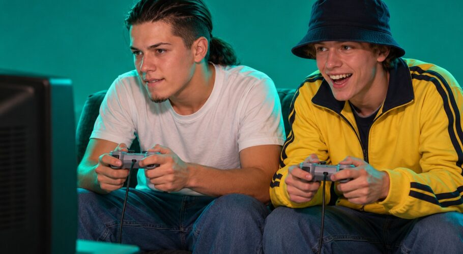 Tony and Shawn sitting on a couch playing PlayStation in front of a CRT television
