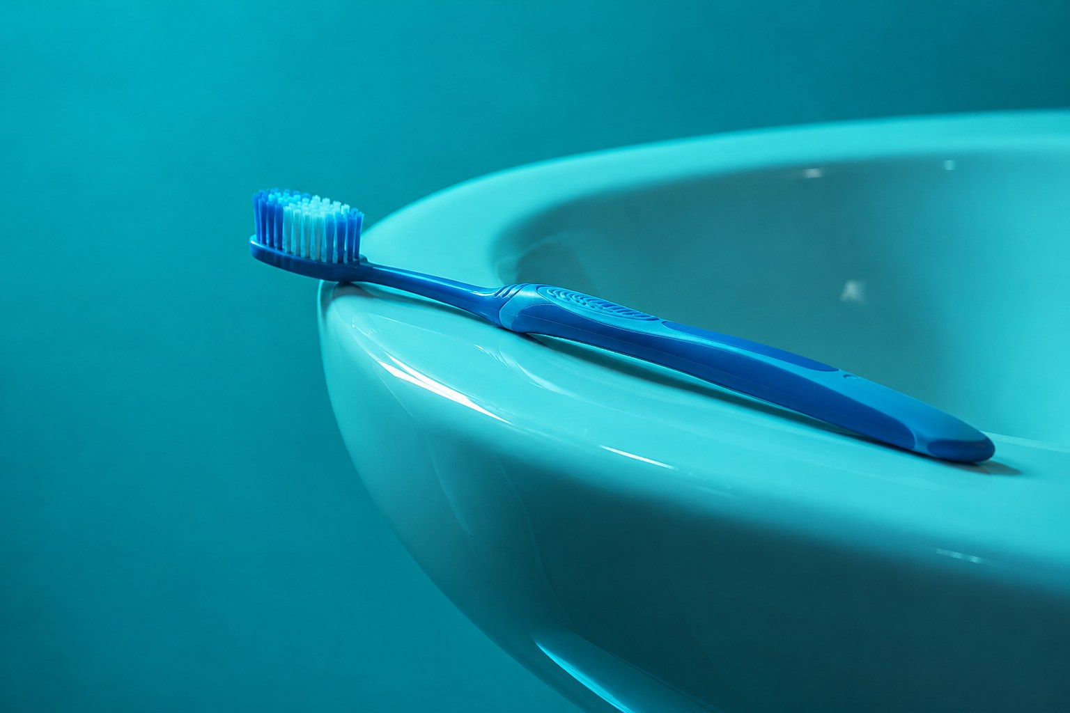 A toothbrush resting on a white ceramic basin