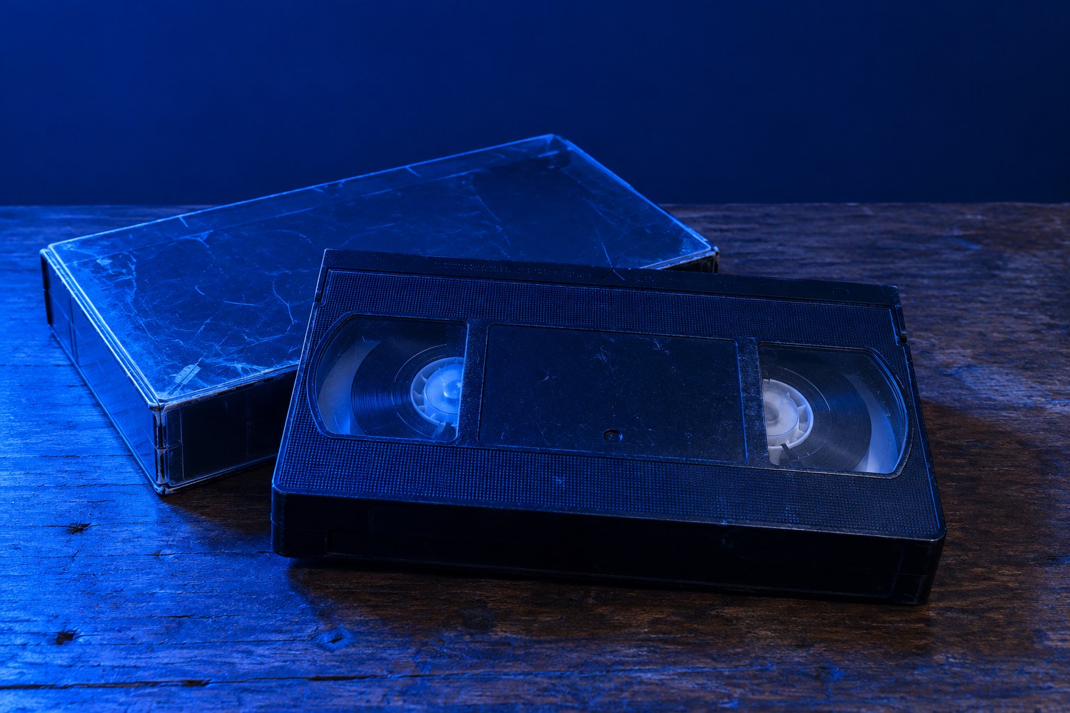 A VHS tape in a rental case on a wooden table under blue light