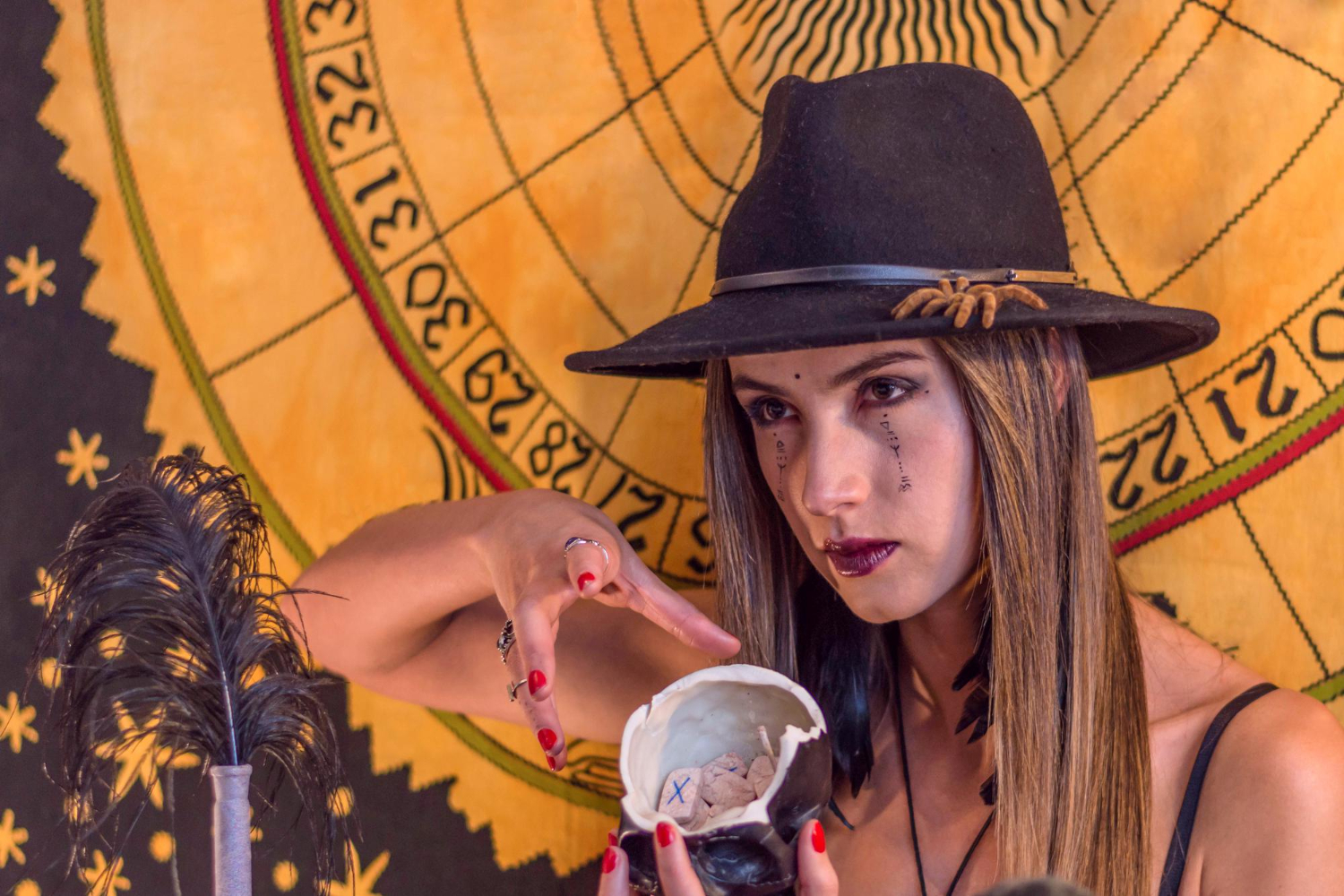 woman esoteric oracle with black hat runic letters writing on her face having seance