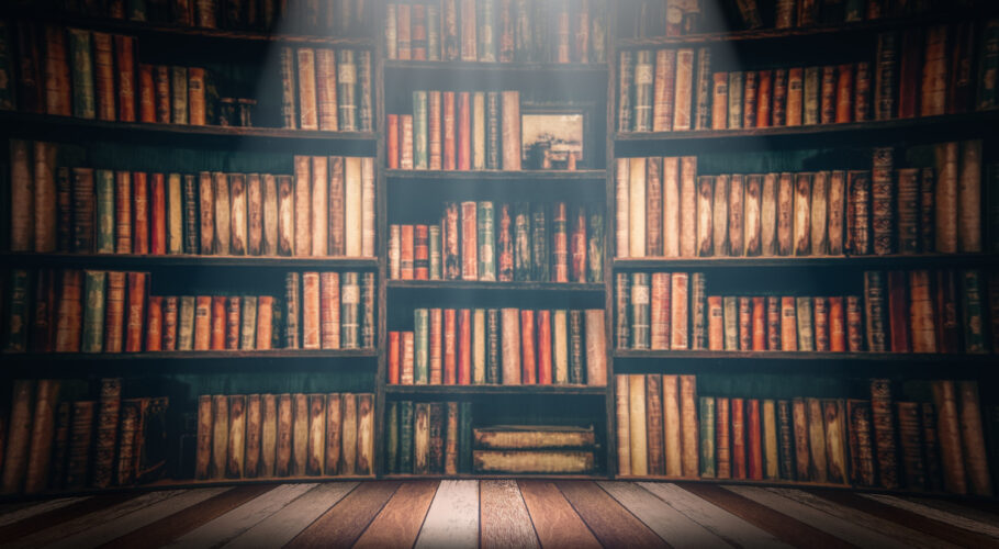 wooden table in a large library full of books and novels
