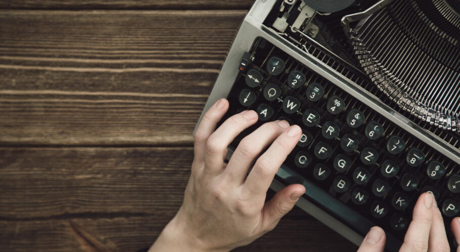writer types on old typewriter on a wooden table